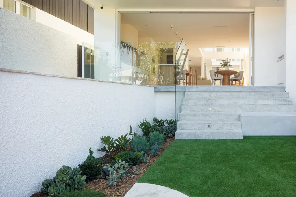 Your Guide to Cement Render: Everything You Need to Know Small backyard with plants stairs leading into a kitchen